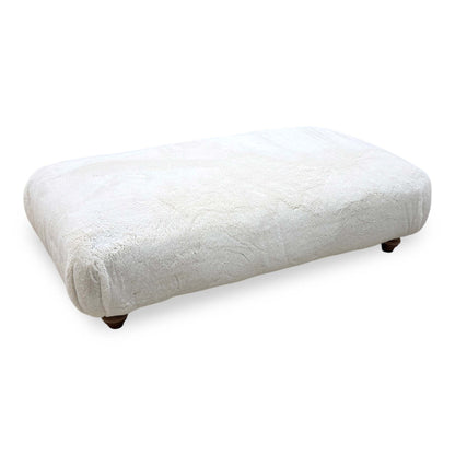 Blenheim Darwin ivory faux fur large footstool on dark wooden bun feet, angled from the right