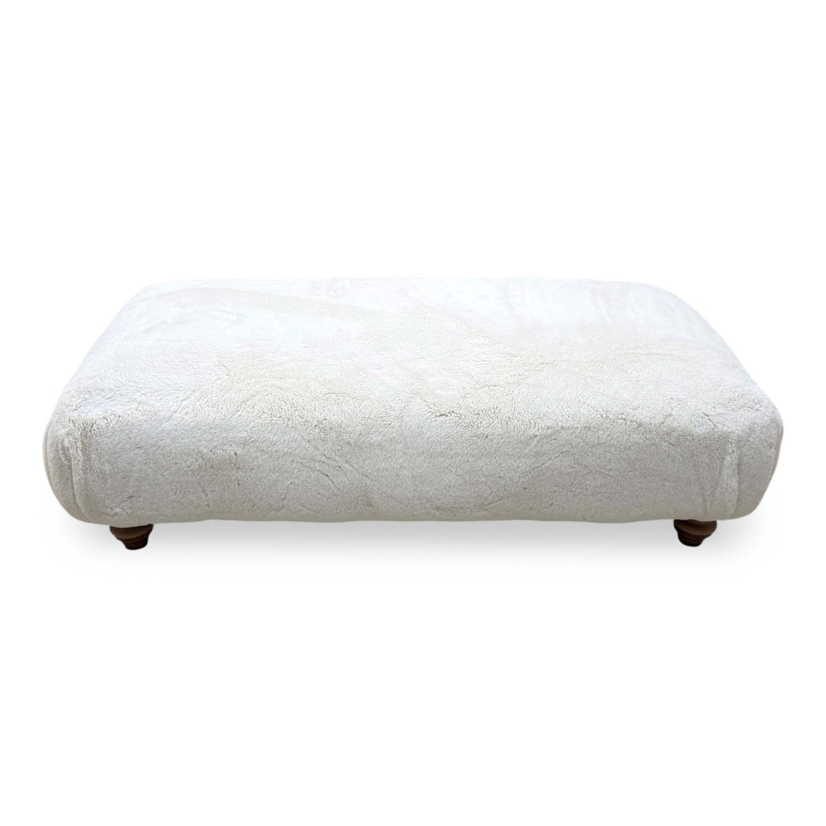 Front view of the Blenheim Darwin ivory faux fur large footstool with dark wooden feet