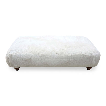 Front view of the Blenheim Darwin ivory faux fur large footstool with dark wooden feet