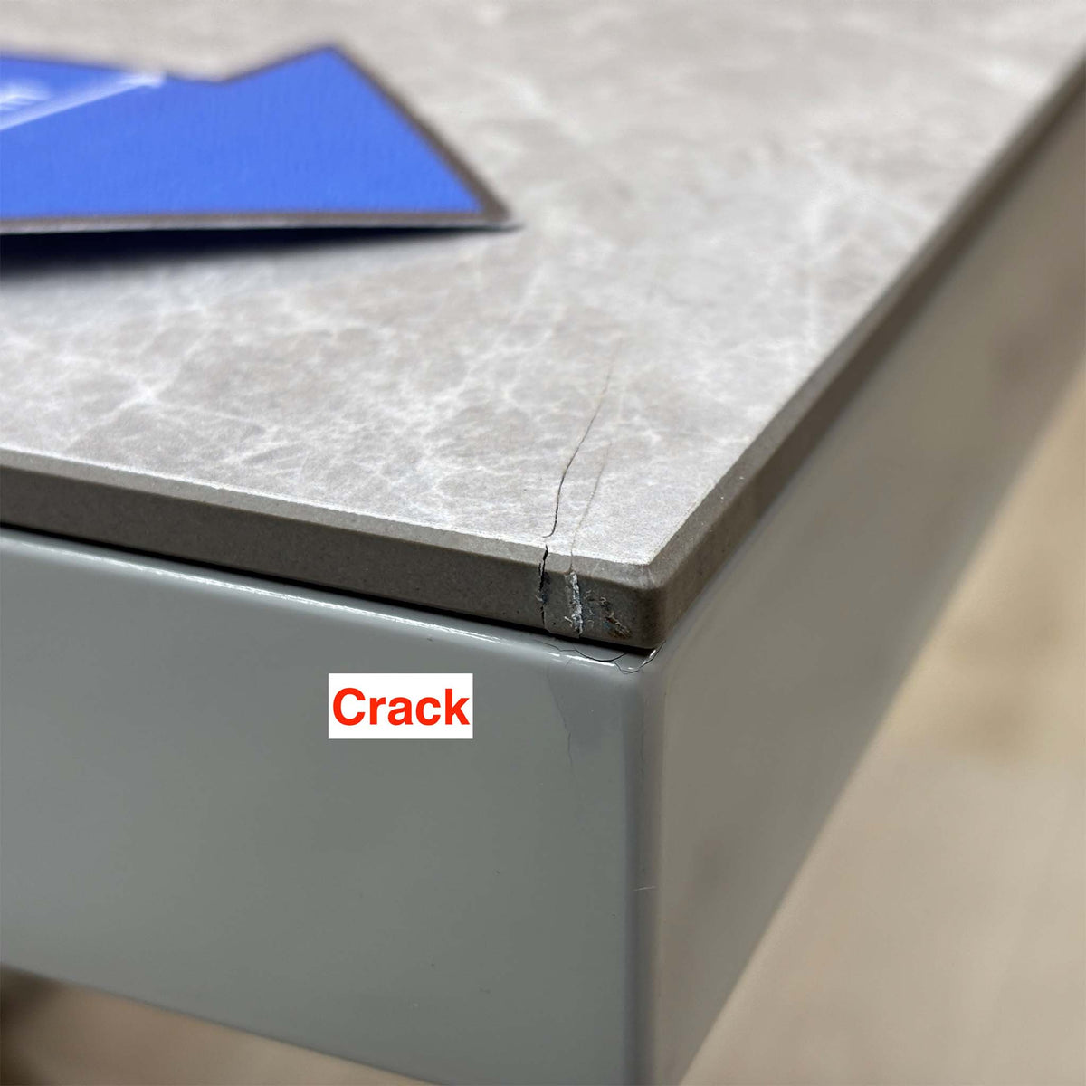 Close-up of the crack running across the corner edge of the Fumo grey marble-effect table top