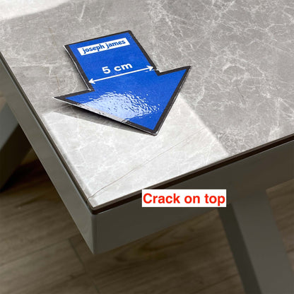 Close-up of the crack on the corner of the Fumo grey marble-effect table top, with a 5cm arrow sticker for scale