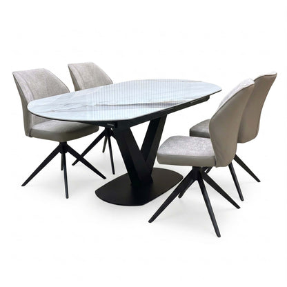 Julio grey-veined marble ceramic 130cm dining table with four cream fabric swivel chairs, angled from the right
