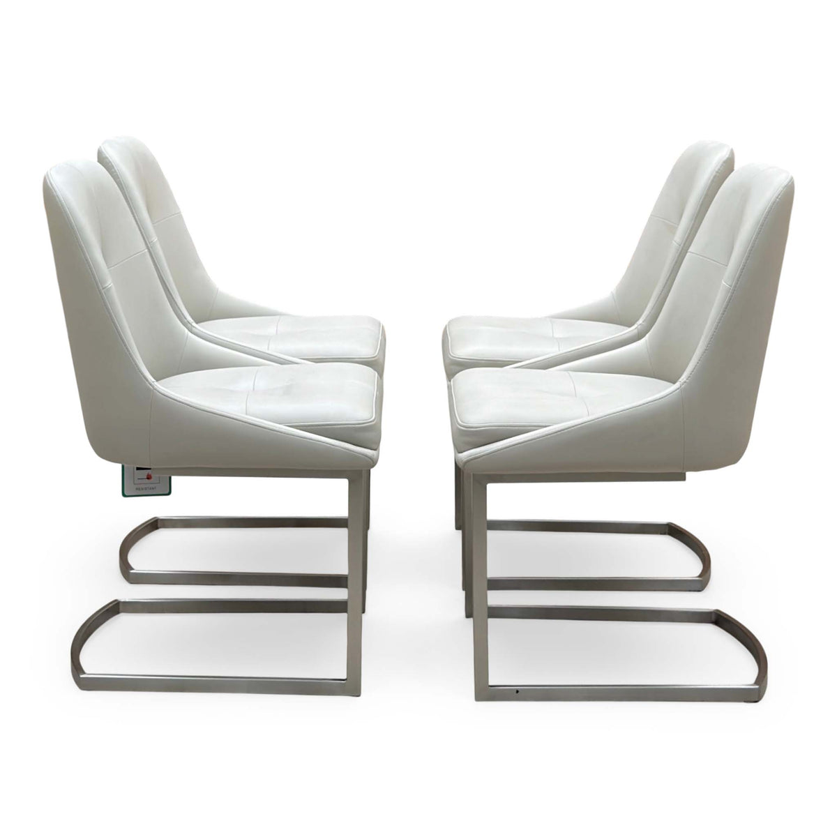 Side view of the four Avorio neutral faux leather dining chairs showing the cantilever metal bases