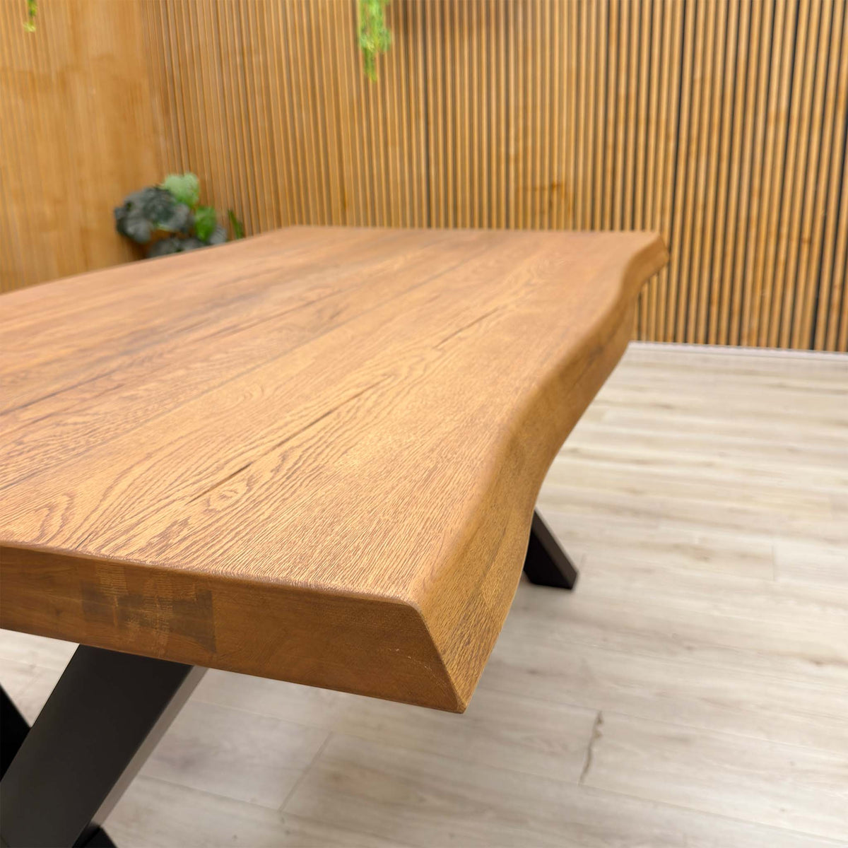 Close-up of the raw edge and oak top of the Bodahl Terra dining table against a slatted wall