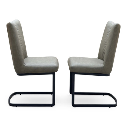 Side view of the Bodahl Loki olive green fabric pair of cantilever dining chairs facing each other on black frames