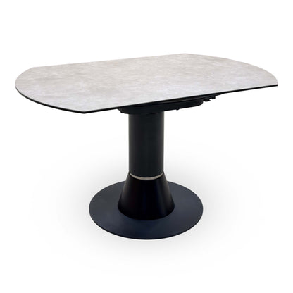 Enterprise grey ceramic top swivel dining table closed to its oval shape, angled view of the black pedestal base