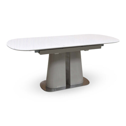 Cashmere white tempered glass top small extending dining table fully extended, angled view on a grey pedestal