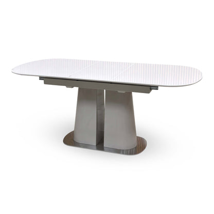 Cashmere white glass top small dining table extended, angled from the right showing the twin pedestal