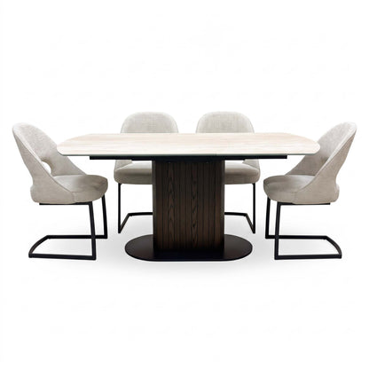 Front view of the Tiber travertine ceramic extending table with four beige cantilever chairs spaced along both sides