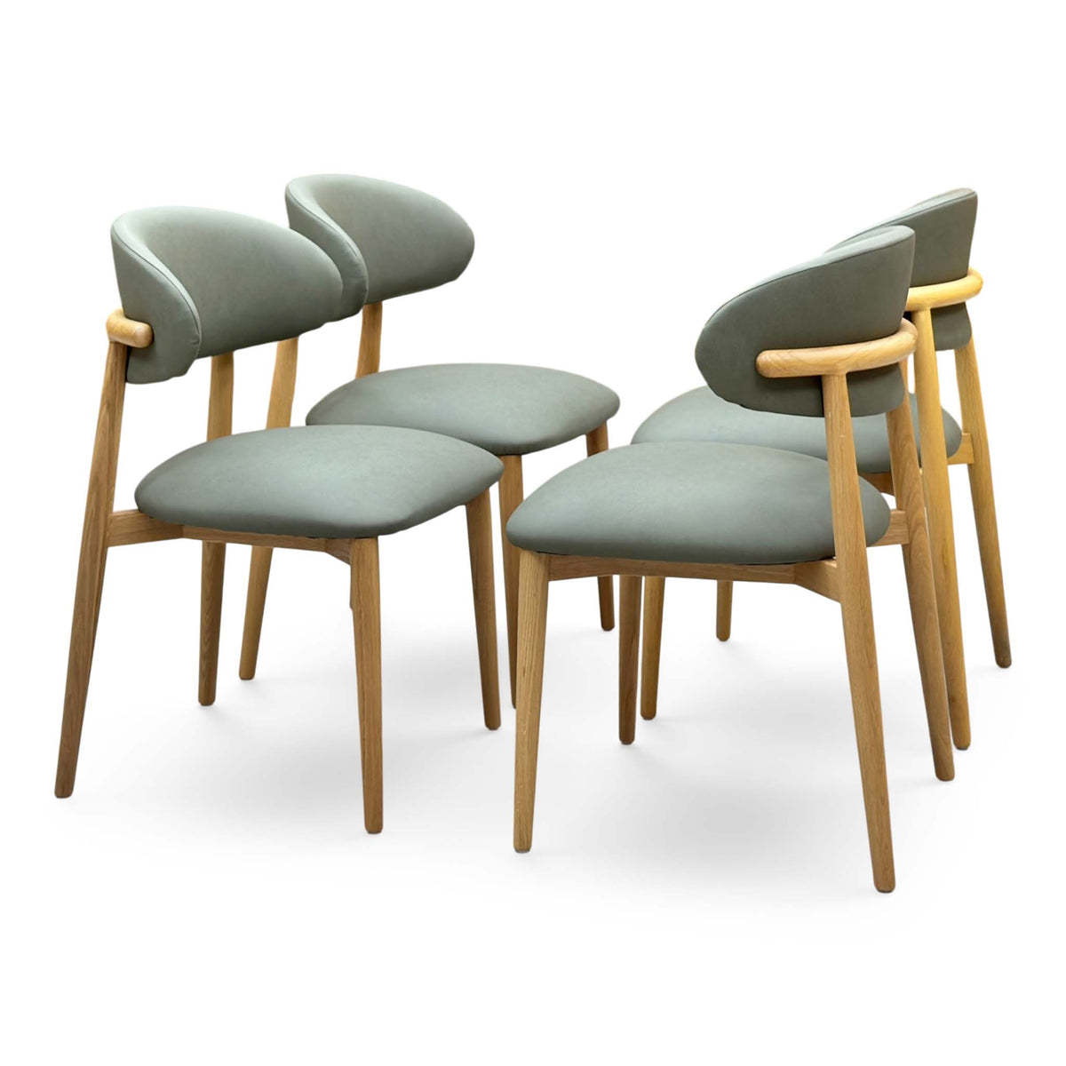 Riga olive green faux leather set of 4 dining chairs with curved open backs on light oak legs, angled view
