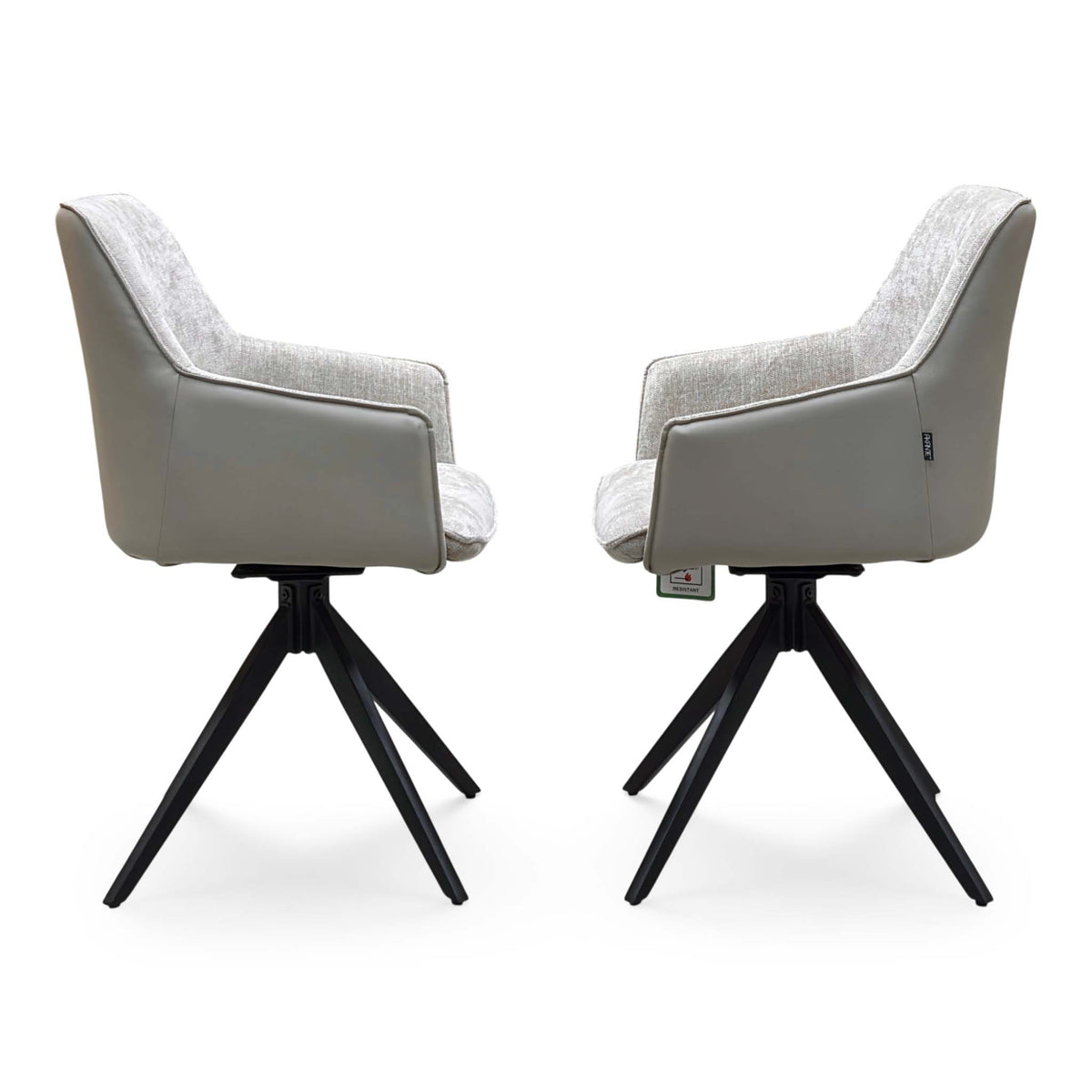 Side profiles of the pair of Jose cream fabric swivel dining chairs on black four-point bases