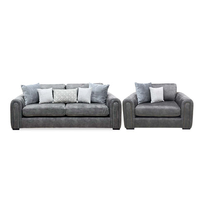 Front view of the Amara charcoal grey velvet 3 seater sofa and snuggle chair with grey and patterned scatter cushions