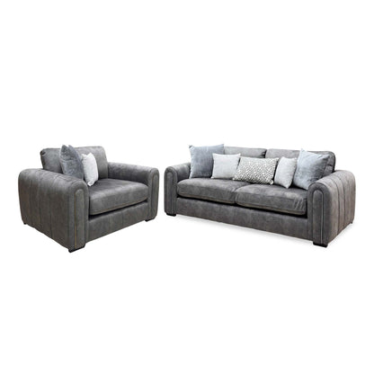 Angled view of the Amara charcoal grey velvet snuggle chair and 3 seater sofa with the snuggle chair on the left
