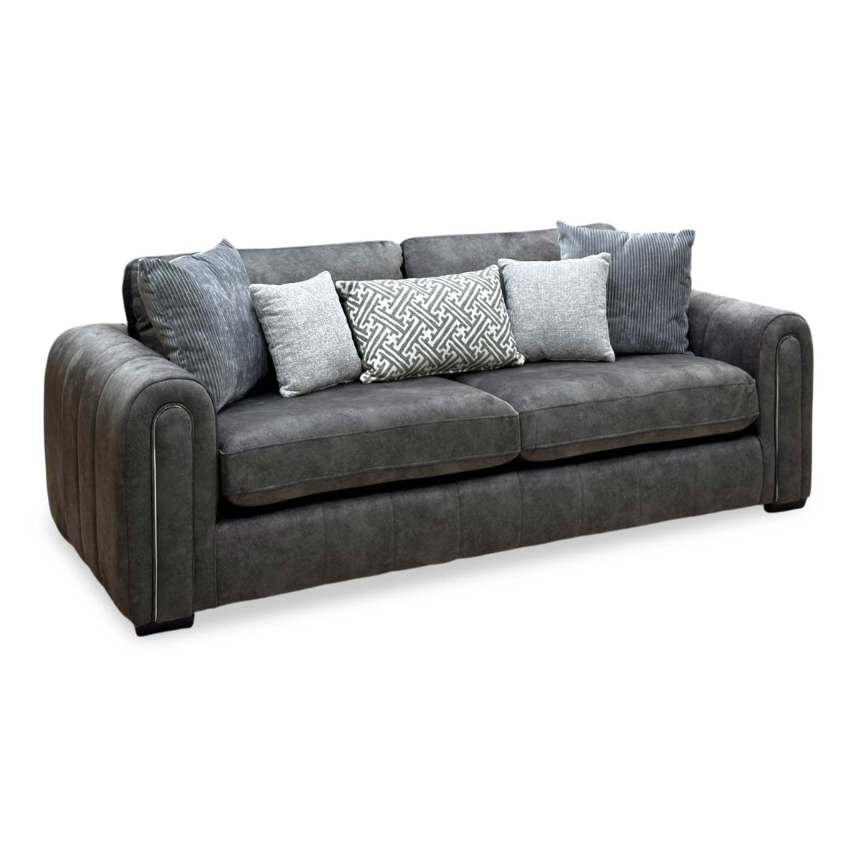 Amara charcoal grey velvet 3 seater sofa, angled view with five grey and patterned scatter cushions