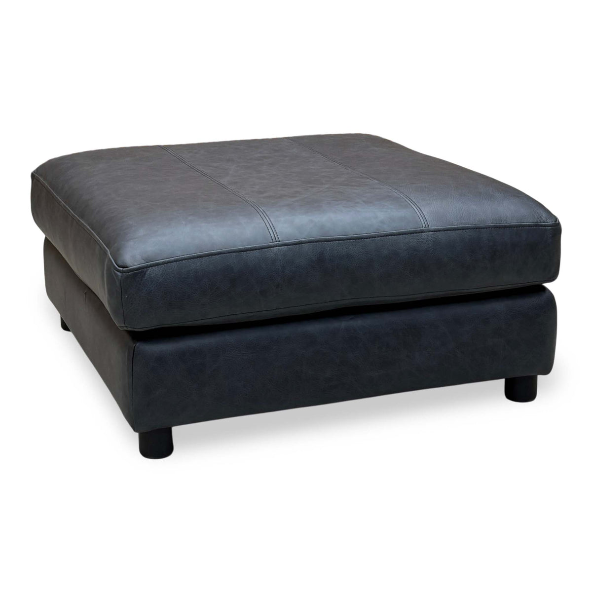 The Lounge Co Romilly shadow navy blue leather footstool, angled view with stitched top and dark feet