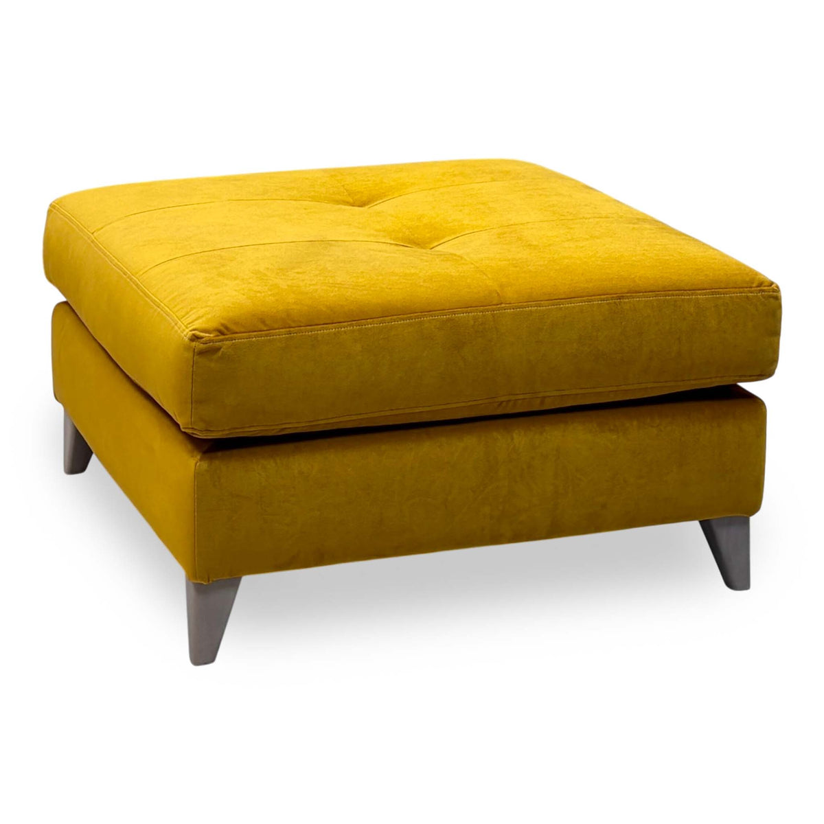 The Lounge Co. Hermione amber yellow velvet footstool with a buttoned top and grey tapered legs, angled view from the left
