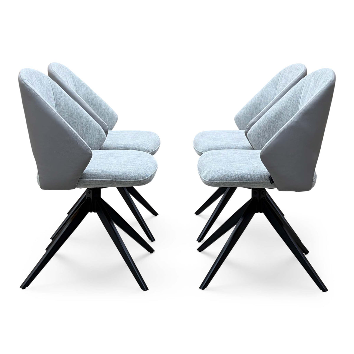 Side angle of the Raul stone grey fabric swivel dining chairs showing the curved backs and spider legs