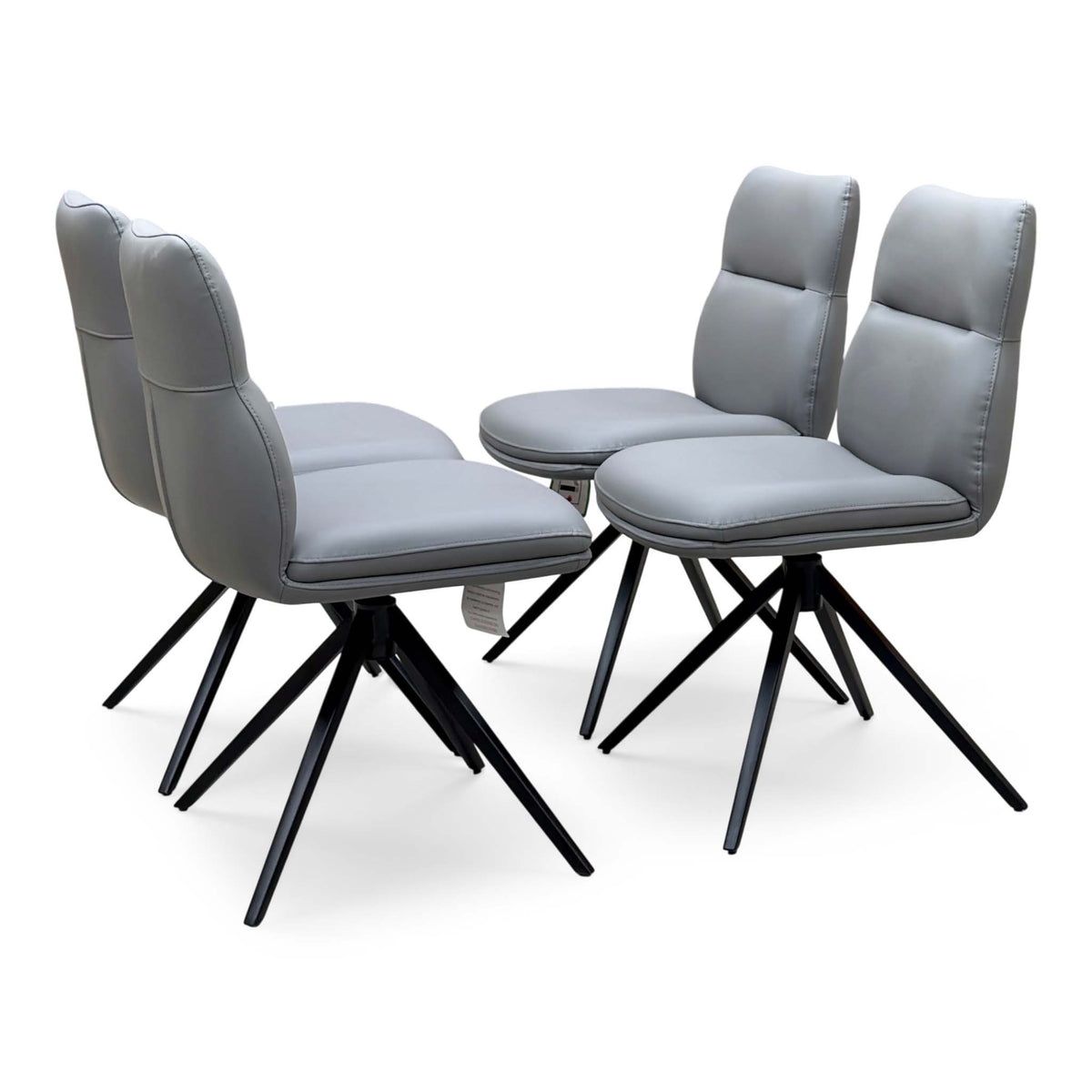 Quattro stone grey faux leather set of 4 swivel dining chairs, angled view with black splayed metal legs