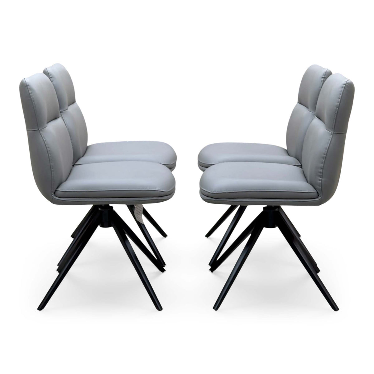 Side angle of the Quattro stone grey faux leather swivel dining chairs showing the padded backs and black legs