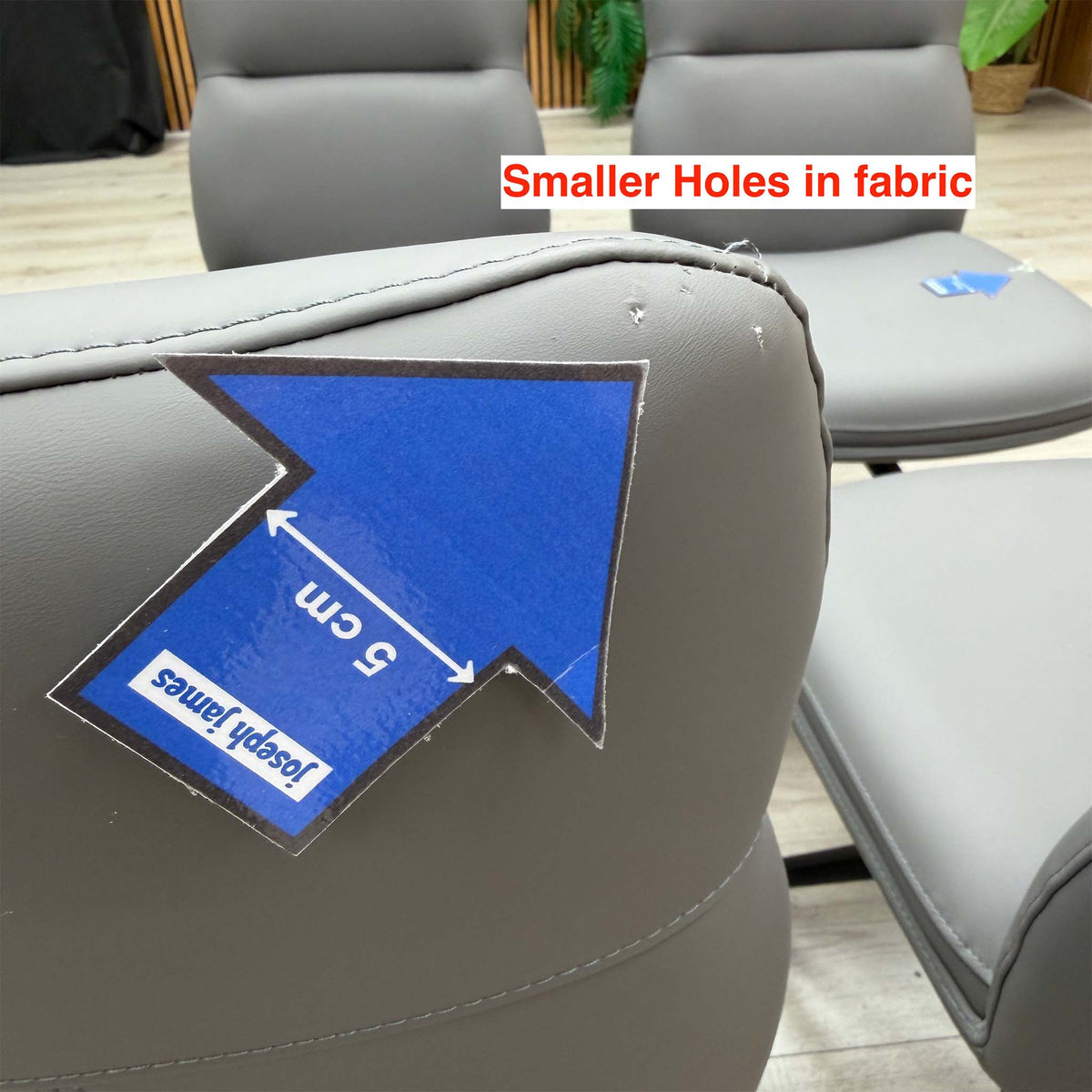 Close-up of the smaller holes in the faux leather on a Quattro stone grey swivel chair back, 5cm arrow for scale