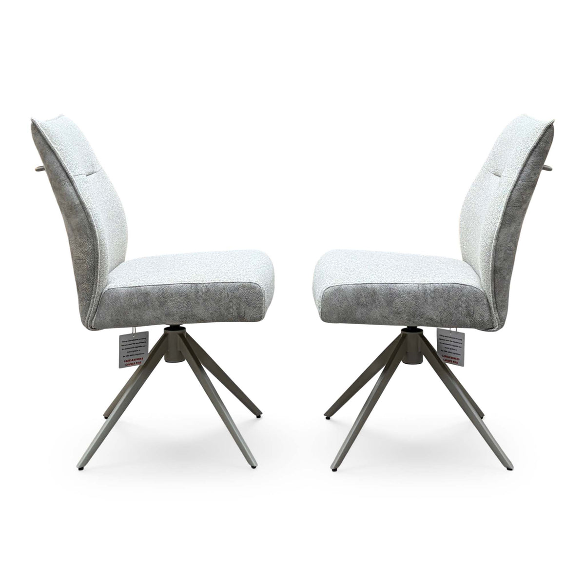 Side angle of the Mirage neutral fabric swivel dining chair pair showing the brushed metal star bases