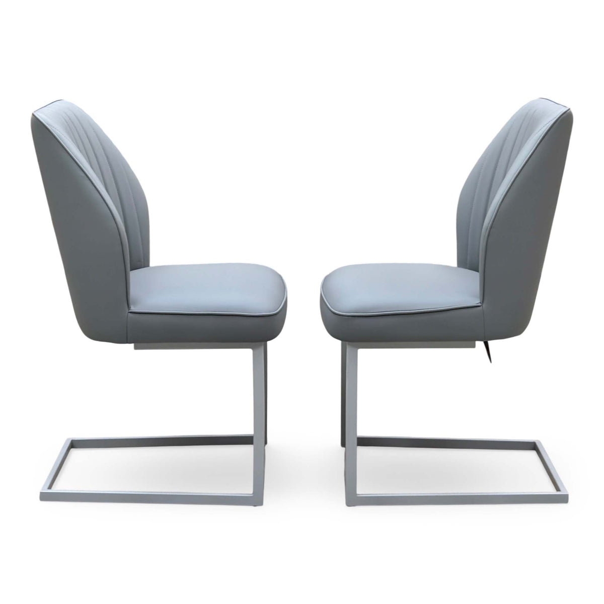 Side profile of the Fumo grey faux leather cantilever dining chairs facing each other showing the chrome frames