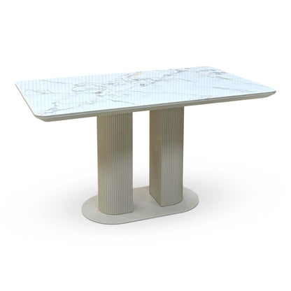 Avorio white marble effect ceramic top fixed dining table on a cream fluted twin pedestal base, angled view