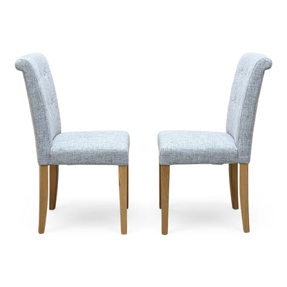 Side angle of the Augusta mist grey fabric pair of roll back dining chairs showing the scroll top and oak legs