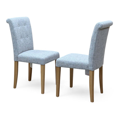 Augusta mist grey fabric pair of roll back dining chairs with buttoned backs, angled from the right