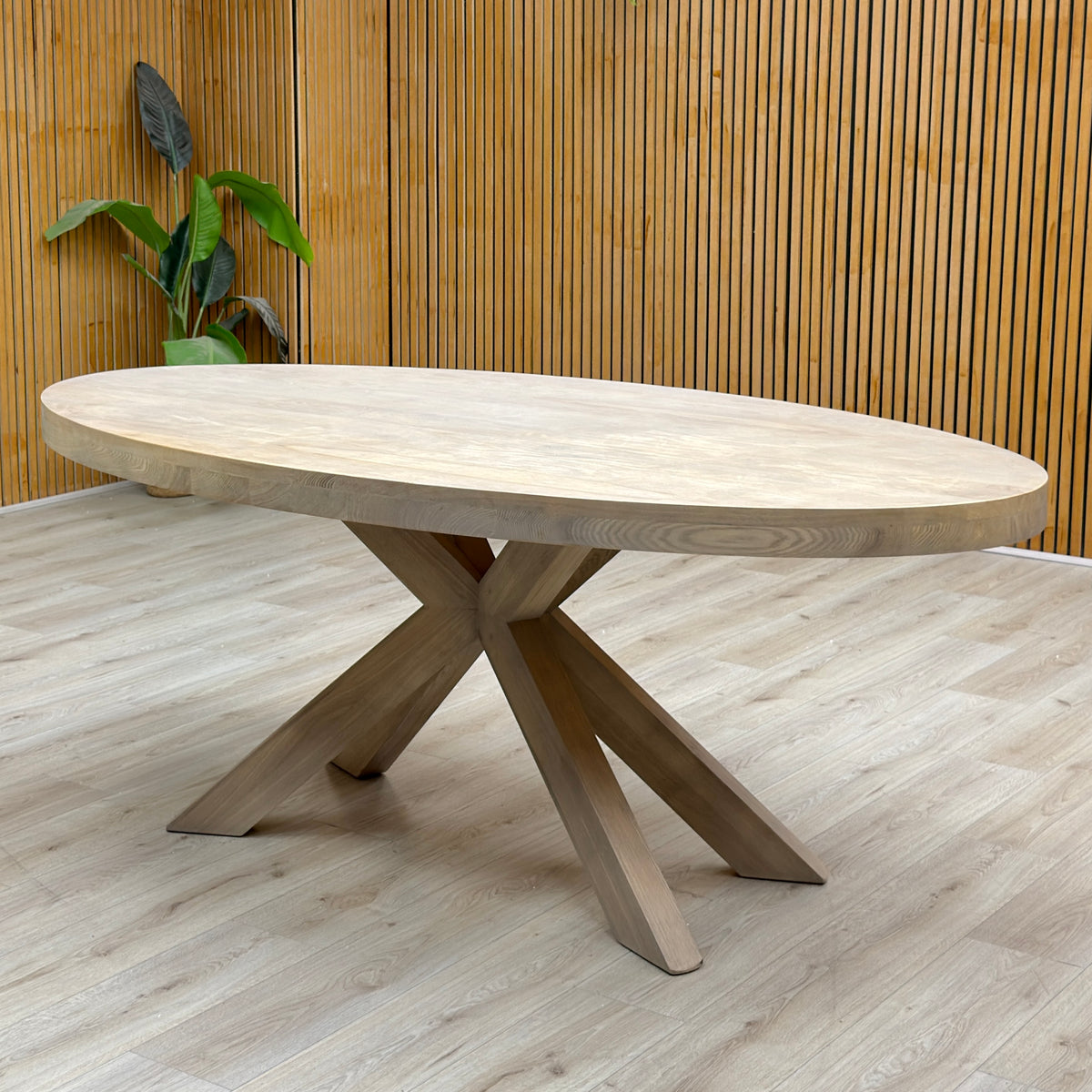 Falun smoked oak small oval dining table against a slatted wooden wall on a light oak floor