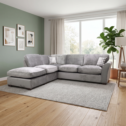 Lifestyle shot of the Rosie grey fabric corner sofa, showcasing its generous seating space and contemporary silhouette in a bright living room.