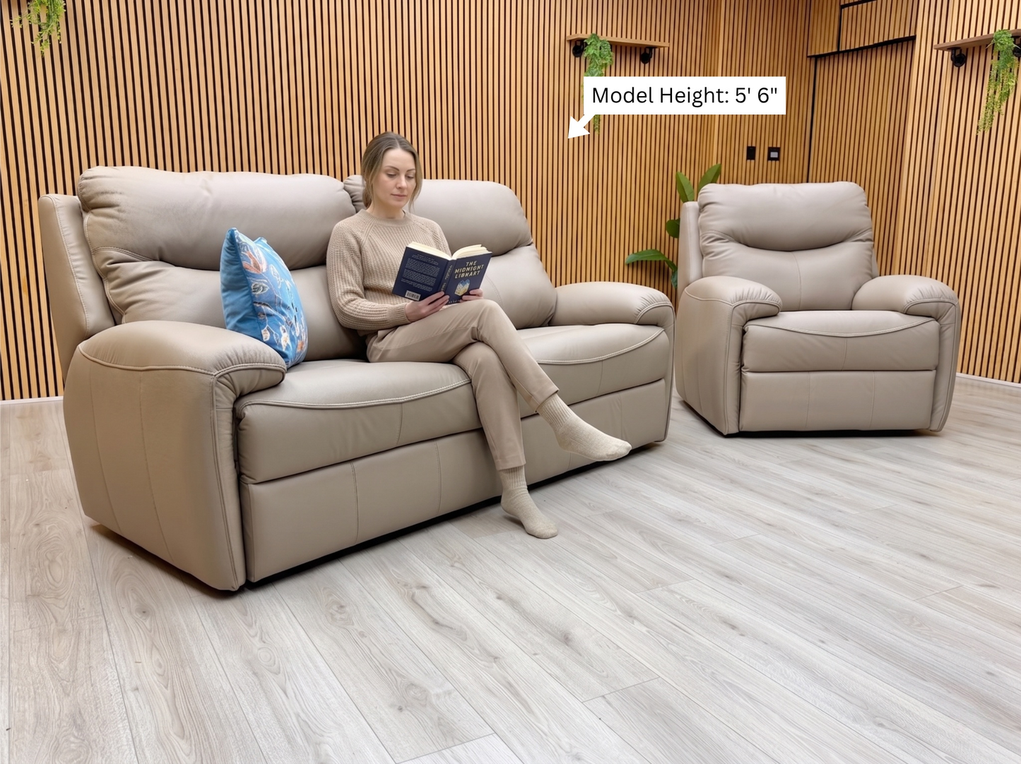 Woman sitting on a beige sofa reading a book in a modern living room.
