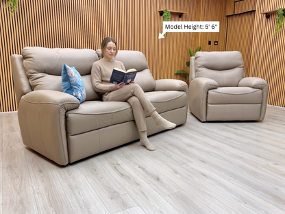 Woman sitting on a beige sofa reading a book in a modern living room.