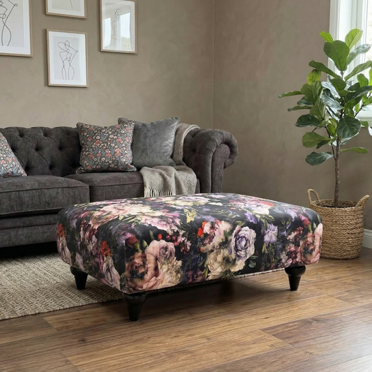 Living room view of the Dame footstool, showcasing the detailed multi-color floral motif and rectangular banquette shape.