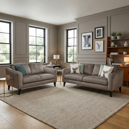 Living room view of three-quarter angled view of the Oslo Vogue stone velvet 3-seater couch, highlighting the slim piped track arms and contemporary low-profile black legs.