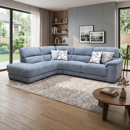 Living room view three-quarter angled view of the Nova silverish blue fabric corner couch, highlighting the deep lounging chaise section, clean track arms, and modern living room profile.