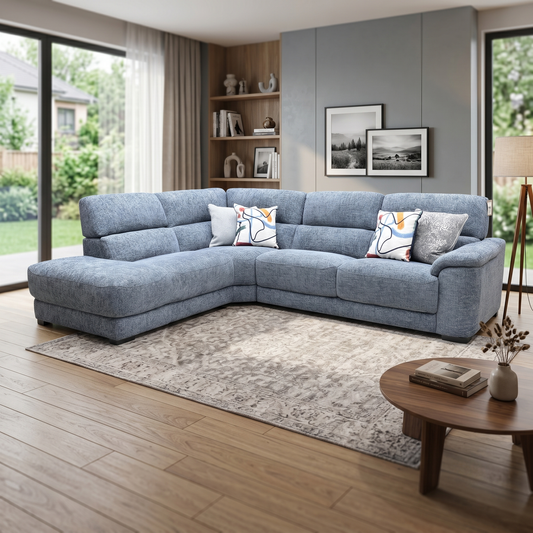Living room view three-quarter angled view of the Nova silverish blue fabric corner couch, highlighting the deep lounging chaise section, clean track arms, and modern living room profile.