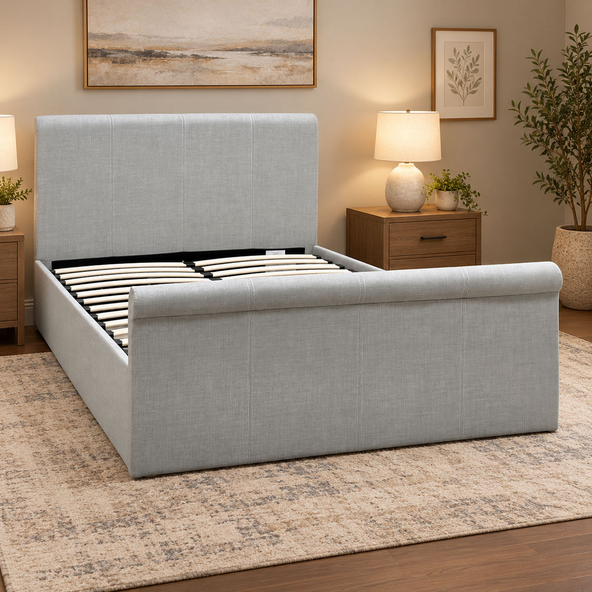 Stanley grey fabric ottoman bed in a bedroom with oak bedside tables, lamps and framed prints