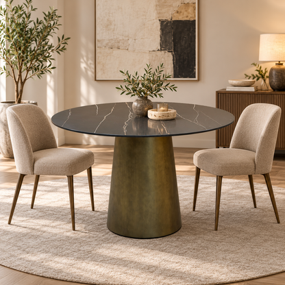 Osiris black and gold veined round dining table in a dining room with two beige chairs and an olive plant