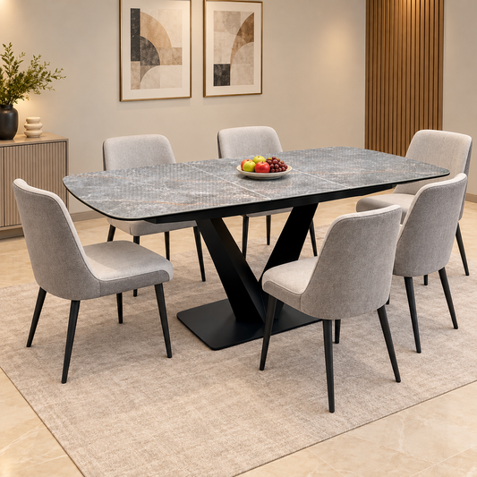 Cupra grey marble effect ceramic dining table extended, in a dining room with six light grey chairs and a fruit bowl
