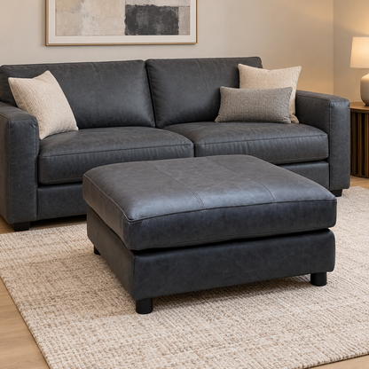 Romilly navy blue leather footstool in a living room in front of a matching sofa with cushions
