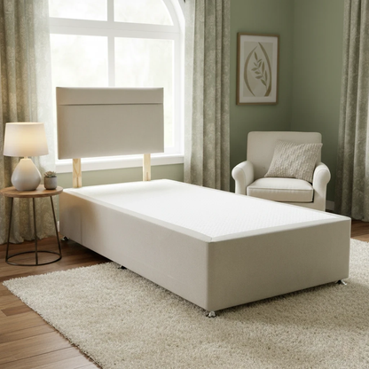 Beige bed in a room with a window, chair, and lamp.