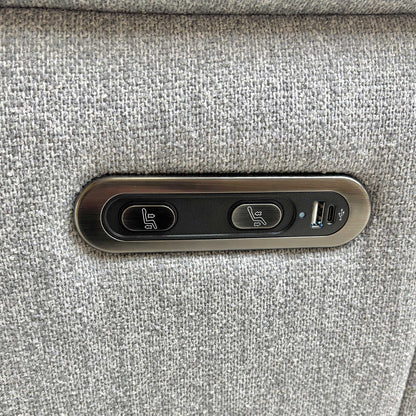 Close-up of the integrated power reclining control buttons on the side of the ‘Bobby’ Florence Stone Grey fabric sofa, showing the motorized adjustment switches.