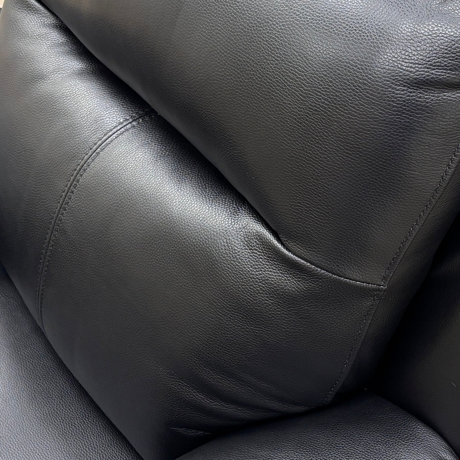 Detail shot focusing on the leather material, stitching, and high-back headrest.