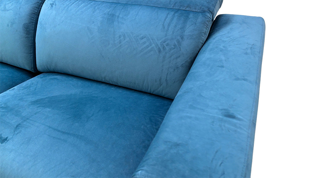 Close-up of the smooth, plush texture of the teal velvet fabric on the Fabb 'Cora' sofa.