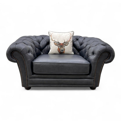 Close-up of the navy blue leather upholstery on the 'Savannah' snuggler chair, emphasizing the smooth texture and solid color.