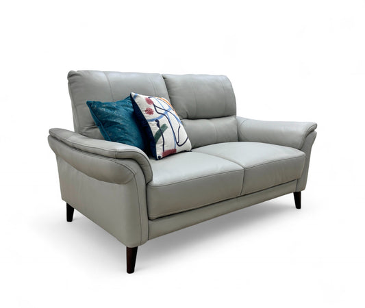 Full, angled front view of the 'Winner' Oslo 2 Seater Sofa, showcasing its light grey leather upholstery, rolled arms, and pocket-sprung seat cushions.