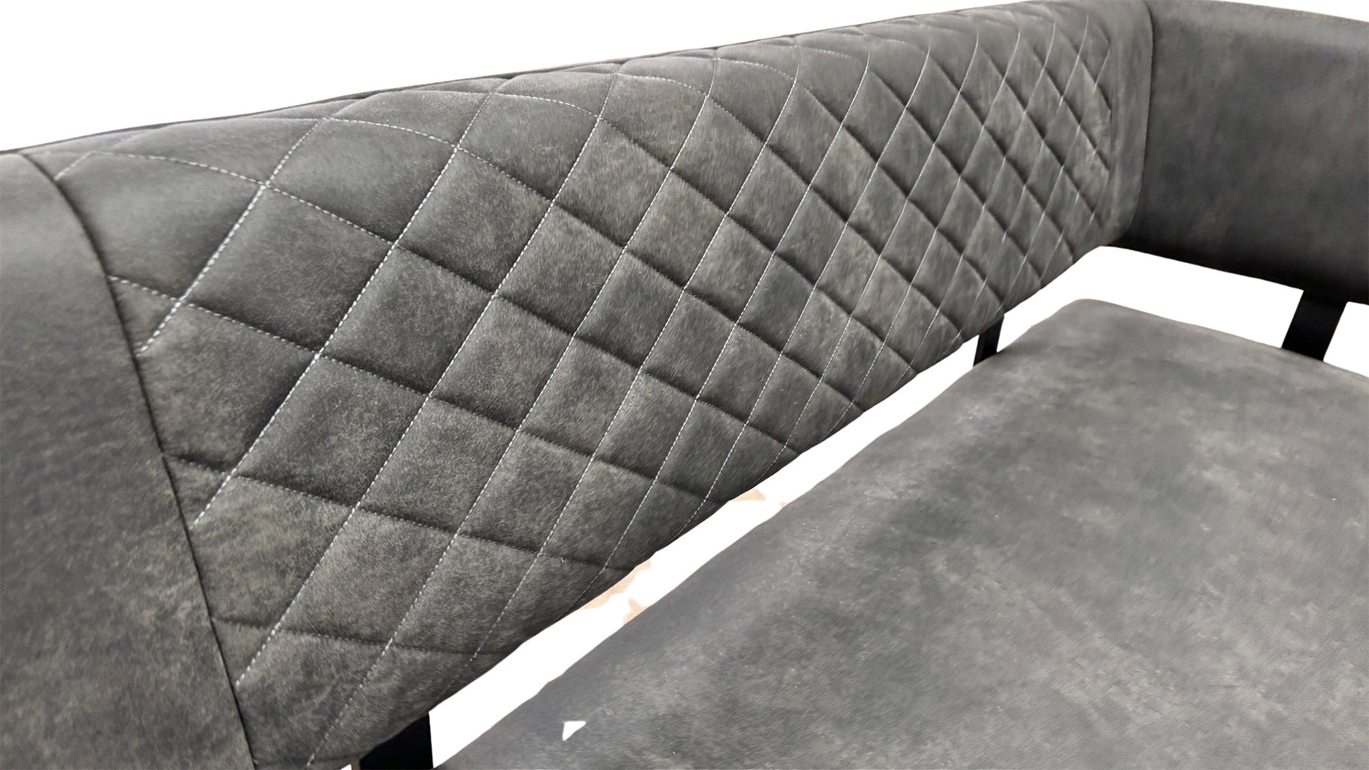 Close-up side view of the corner bench, showcasing the high backrest, the quilted stitching pattern on the grey fabric, and the metal legs.