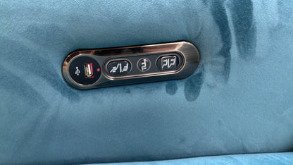 Close-up of the built-in power control buttons, often located on the side of the seat, for activating the recliner and adjusting the headrest on the 'Cora' sofa.