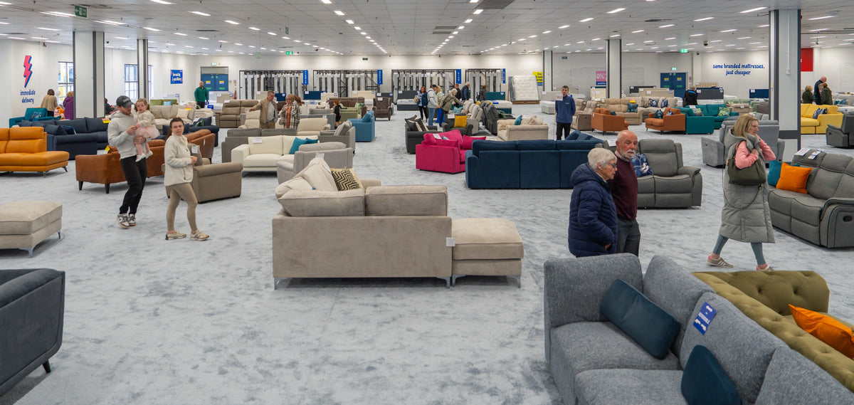 Furniture store with various couches and people browsing in a large open space.